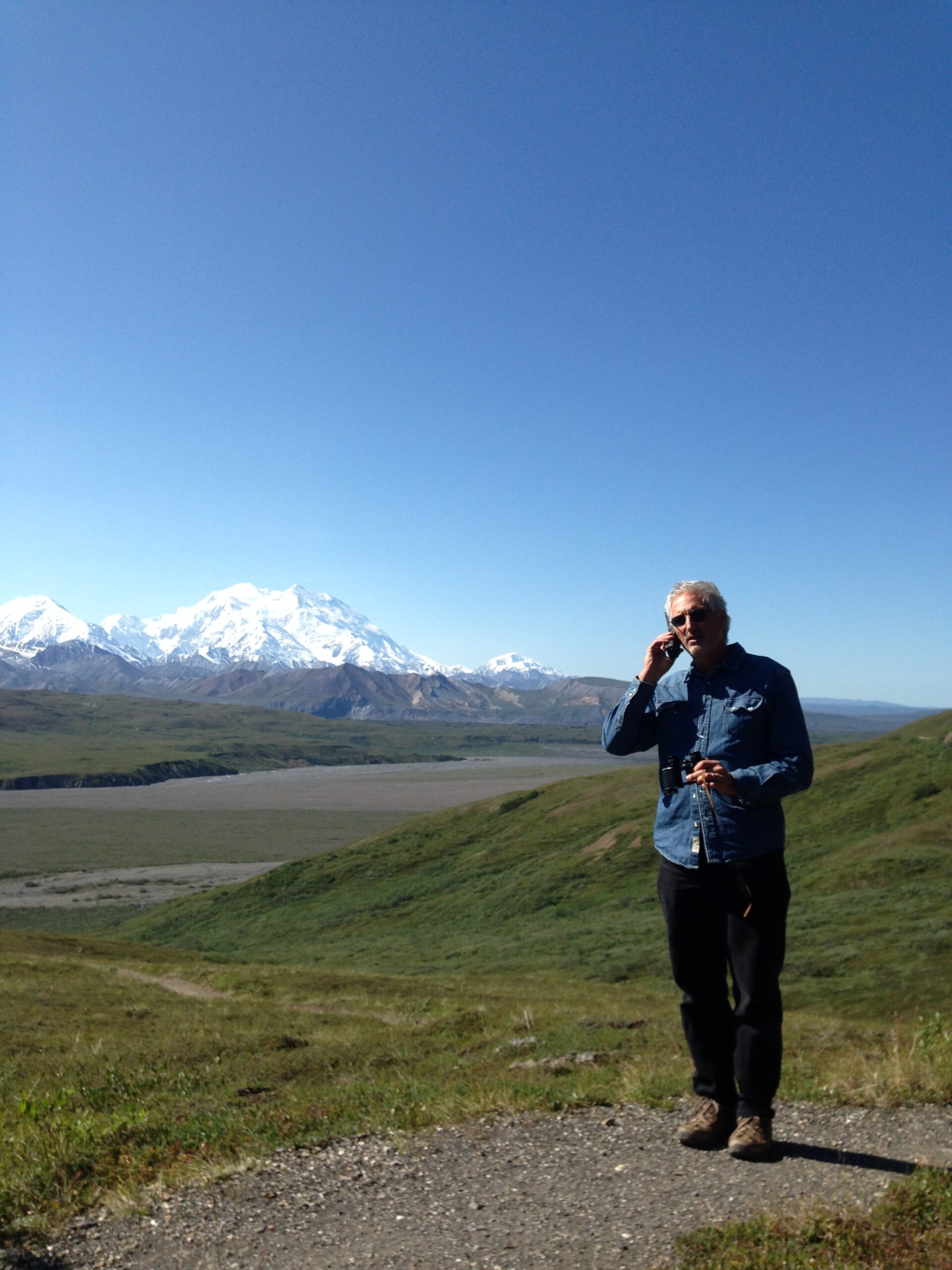 A man talking on a satellite phone while standing in open wilderness